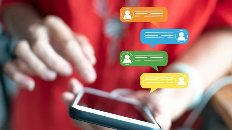 Hands holding a smartphone with colourful chat message bubbles